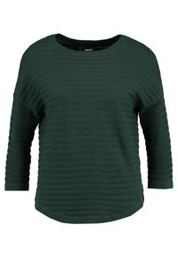 Top de manga larga de color verde oscuro, con cuello redondo y dobladillo ligeramente curvado. Hecho de una tela texturizada con un ajuste relajado.