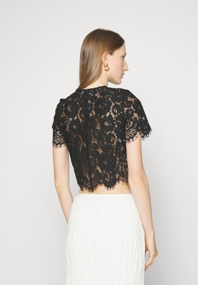Čierny čipkový crop top s krátkymi rukávmi, kvetinovým vzorom a zúženým lemom. Obsahuje priesvitnú textúru a zapínanie na chrbte.