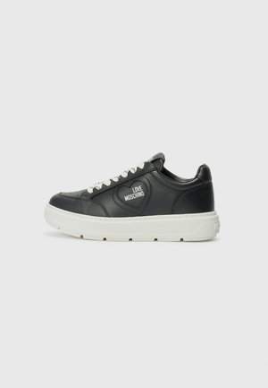 Zwarte leren sneakers met witte zolen, voorzien van een hartvormig logo en witte veters. Gladde textuur en afgerond ontwerp.