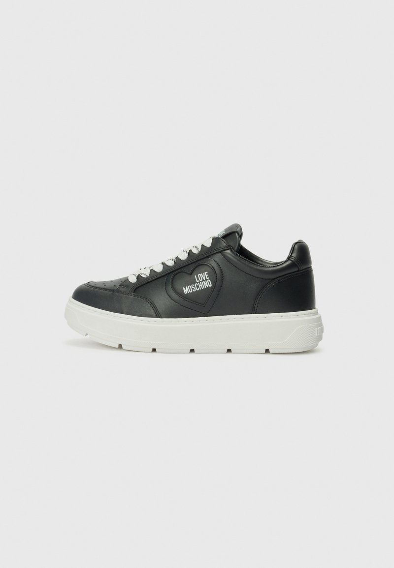 Zwarte leren sneakers met witte zolen, voorzien van een hartvormig logo en witte veters. Gladde textuur en afgerond ontwerp.