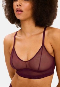 Bordeaux bralette met een doorzichtige meshontwerp, verstelbare bandjes en gegolfde randen. Beschikt over een gestructureerde vorm en een gladde textuur.