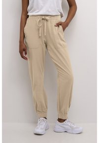 Beige, leichte Jogginghosen mit elastischem Bund, gebundenem Kordelzug und Seitentaschen. Umschlagbündchen und glatte Textur.