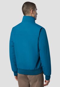 Giacca a vento blu con colletto alto e polsini a coste. Texture liscia con un design leggero, adatta per un abbigliamento casual.