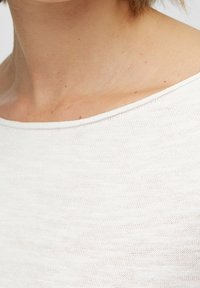 Lekki, off-white sweter o lekko luźnym kroju, z szerokim dekoltem i subtelną, teksturowaną tkaniną.