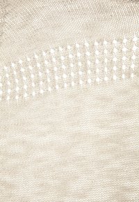 Tessuto in maglia beige chiaro con una superficie texturizzata caratterizzata da punti aperti e uno sfondo liscio, che mette in risalto una leggera lucentezza.
