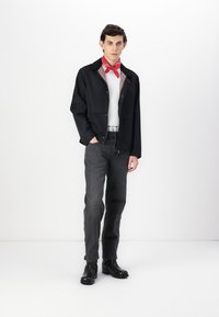 Black lightweight jacket, white shirt, red scarf, gray jeans, and black boots. Smooth texture, casual design with snap closures and accents.
