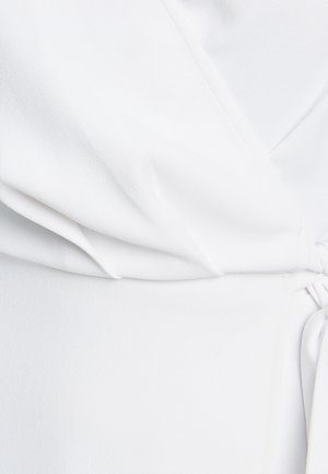 Bijela, teksturirana tkanina s naboranim dizajnom i čvorom s jedne strane. Glatka površina s suptilnim sjajem i drapiranim izgledom.