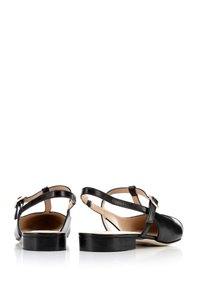 Zapatos slingback de cuero negro con un tacón bajo, que cuentan con correas ajustables, un acabado suave y una plantilla acolchada.