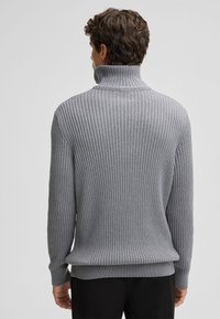 Maglione a coste grigio con colletto alto, caratterizzato da un motivo testurizzato e una vestibilità rilassata. I polsini e l'orlo sono a coste per un tocco aggiuntivo.