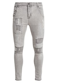 Grå denim skinny jeans med slitna lappar, fransiga kanter och en blekt finish. Har framfickor och knappstängning.