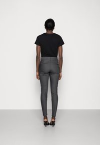Black t-shirt and fitted gray trousers with a smooth texture. The trousers have two back pockets and are paired with black heels.