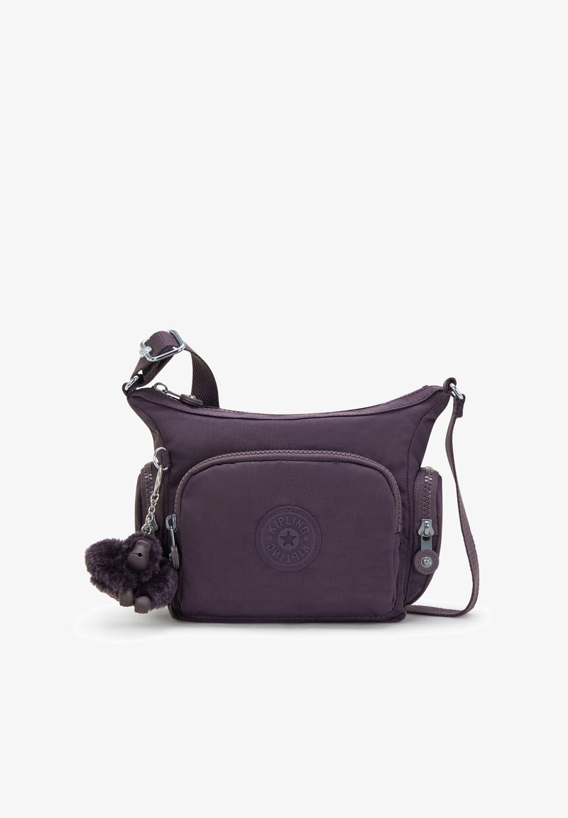 Borsa a tracolla viola in nylon con tracolla regolabile, tasca frontale con zip e un portachiavi a forma di gorilla peloso attaccato. Presenta una patch con logo testurizzato.
