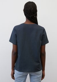 Mørkeblå kortærmet t-shirt lavet af bomuld med rund halsudskæring og en afslappet pasform. Synlige sømme og et lille mærke ved bundsømhullet.