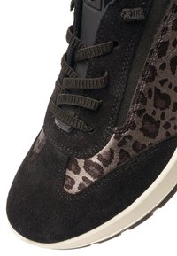 Close-up of a black sneaker with suede and leopard print panels, black laces, and a white sole.