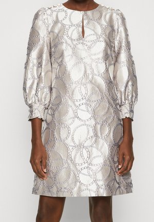 White textured dress with silver chain-link circle pattern, three-quarter puff sleeves, button details on shoulders, and front keyhole neckline.