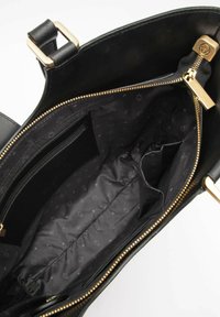 Wnętrze czarnej skórzanej torebki z złotym zamkiem błyskawicznym. Funkcje obejmują kieszeń na zamek, wiele przegródek oraz materiałową podszewkę w wzór.