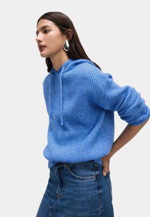 Sweat à capuche bleu clair en maille avec texture côtelée et capuche à cordon, associé à une jupe en denim. Caractéristiques : coupe décontractée et manches longues.