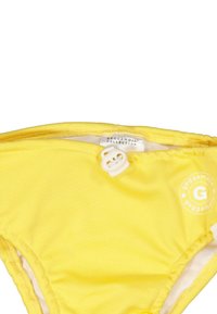 Keltainen bikinitoppi tekstuuripinnalla, elastisilla nauhoilla ja valkoisella nappisuljennalla. Oikealla puolella on logopaino.