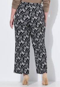 Zwart-witte, gestreepte wijde broek met een bloemenpatroon. Gemaakt van een soepel stof, met een hoge taille en een enkel-lange snit.