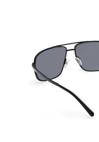 Svartmetallsolglasögon med grå linser, med en tunn trådram och klara nässkydd, designade med en elegant, vinkelrät form.