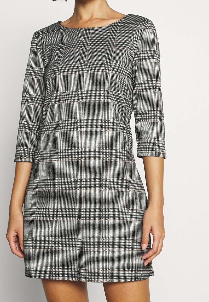 Sukienka w czarno-białą kratę, z rękawami 3/4, dekoltem typu łódka i dopasowanym krojem, wykonana z gładkiej tkaniny o lekkim rozciągnięciu.