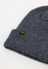Dark blue knit beanie with a folded cuff, featuring a small black label with a yellow logo. Soft texture with a heathered effect.