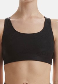 Svart sportbh i stretchmaterial med rundad halsringning och breda axelband. Diskret präglat logomönster över hela tyget.