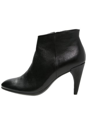 Bottine en cuir noir avec bout pointu et talon fin de hauteur moyenne, texture lisse, fermeture éclair latérale.