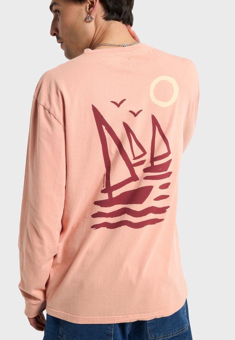 Maglietta in cotone rosa a maniche lunghe con grafica color mogano raffigurante barche a vela, onde, uccelli e sole, con vestibilità comoda e scollatura rotonda.