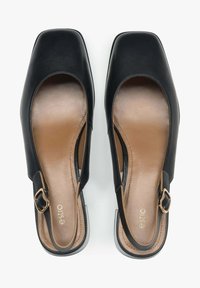 Černé kožené slip-on boty se čtveratou špičkou, otevřenými stranami, hladkou béžovou stélkou a zlatým akcentem přezky. Texturovaná podrážka.