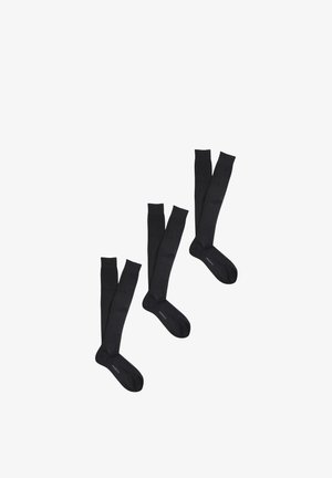 Tre paia di calzini neri a coste al ginocchio con la scritta "PROFILE" stampata vicino alle dita dei piedi, esposti su uno sfondo bianco.