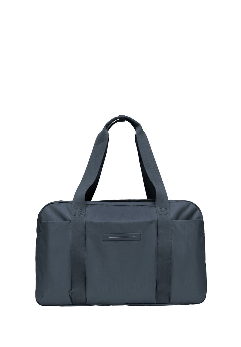 Sac de voyage en tissu gris avec deux poignées robustes, de forme rectangulaire et un détail d'accent horizontal à l'avant. Texture lisse, design minimaliste.