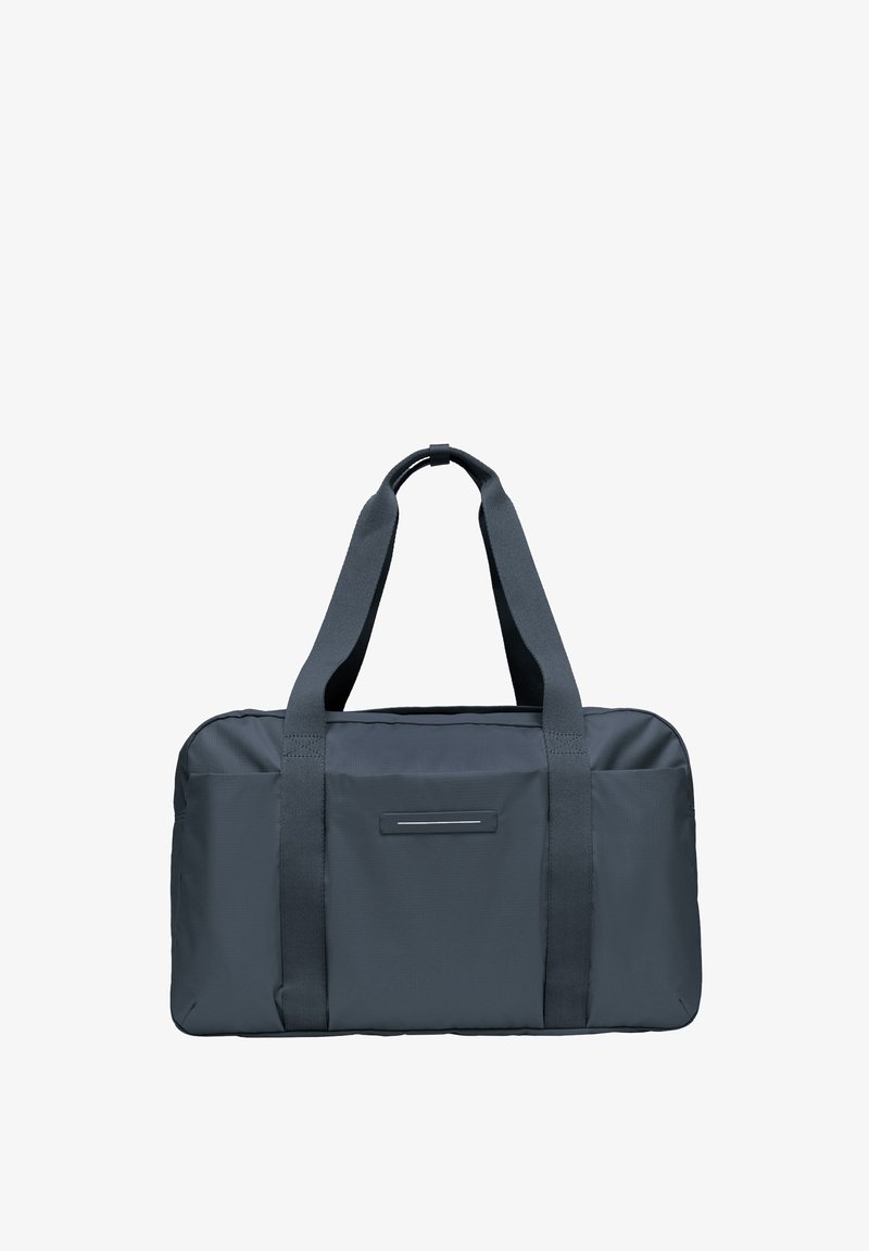 Sac de voyage en tissu gris avec deux poignées robustes, de forme rectangulaire et un détail d'accent horizontal à l'avant. Texture lisse, design minimaliste.