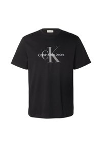 Camiseta de algodón negra con el logo de "Calvin Klein Jeans" en blanco y gris. Mangas cortas, cuello redondo y corte holgado.