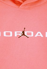 Κόραλλι φούτερ με κουκούλα, διαθέτει τσέπη καγκουρό, απαλό υφασμάτινο υλικό, με λευκό λογότυπο "JORDAN" και μαύρη φιγούρα Jumpman στην πρόσοψη.