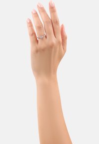 Anello d'argento con una pietra preziosa rotonda centrale, fiancheggiata da due pietre più piccole, incastonato su una sottile fascia, indossato su una mano con tono di pelle chiaro.