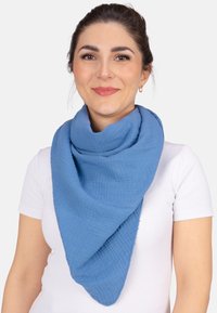 Écharpe en coton bleu en forme triangulaire, avec un motif tissé texturé et un tissu doux et léger. Les bords sont légèrement effilochés.