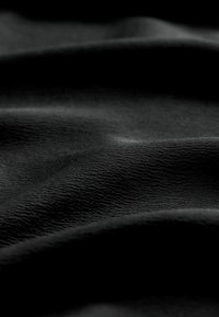 Black fabric with a smooth, slightly wrinkled texture, showcasing subtle variations in sheen and a rich, deep color.