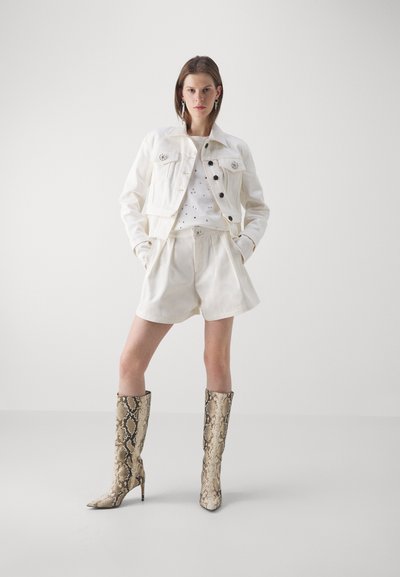 White denim jacket with black buttons, paired with a white shirt featuring subtle patterns and white shorts. Knee-high snakeskin boots with heels.