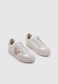 Zapatillas de cuero blancas con acentos de ante beige, diseño de cordones, puntera redondeada y suela de goma. Branding minimalista en la lengüeta.