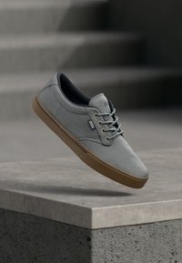 Γκρι καμβά αθλητικά παπούτσια με χαμηλό προφίλ, στρογγυλή μύτη, σχέδιο με κορδόνια, σκούρο εσωτερικό και ανοιχτό καφέ ελαστική σόλα. Απλή σήμανση στο πλάι.