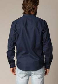 Navyblauwe blouse met lange mouwen van katoen, voorzien van een button-down kraag, rugpas en verstelbare manchetten met knopen.