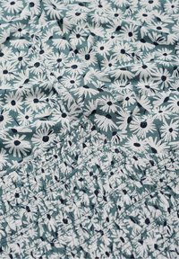 Tela estampada floral con un fondo color aqua y margaritas blancas con centros negros. La sección inferior está fruncida con costura elástica.