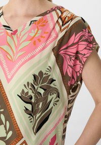 Kurzarmoberteil mit V-Ausschnitt, aus leichtem Stoff mit mehrfarbigen Blumenmustern auf cremefarbenem Hintergrund.