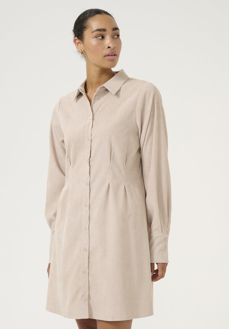 Robe à boutons beige pâle en tissu rayé, avec un col, des manches longues et des détails froncés à la taille.