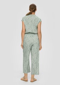 Groene jumpsuit met een patroon, korte mouwen, elastische taille en brede pijpen, met een geometrisch wit ontwerp en een gladde stoftextuur.