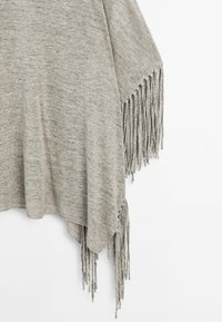 Grau gestricktes Poncho mit Fransenkanten. Die Komposition weist ein strukturiertes Gewebe und eine lockere, hängende Silhouette auf.