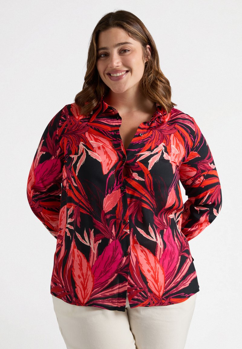 Camisa de botones con fondo negro que presenta vibrantes patrones botánicos en rosa y rojo. Mangas largas, corte ajustado, tejido ligero.