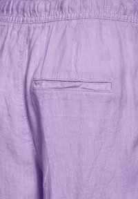 Lilac linen pants with an elastic waistband, featuring a single straight pocket on the back, showcasing a smooth, textured fabric.