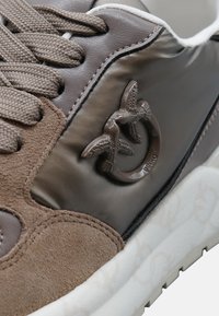 Sneaker in pelle marrone e suede con lacci intrecciati, logo di uccello in rilievo e suola in gomma testurizzata e a contrasto.